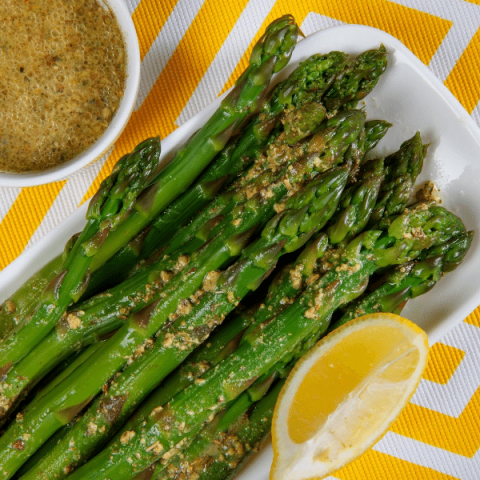 asparagus on a white plate with mustard vinaigrette on top
